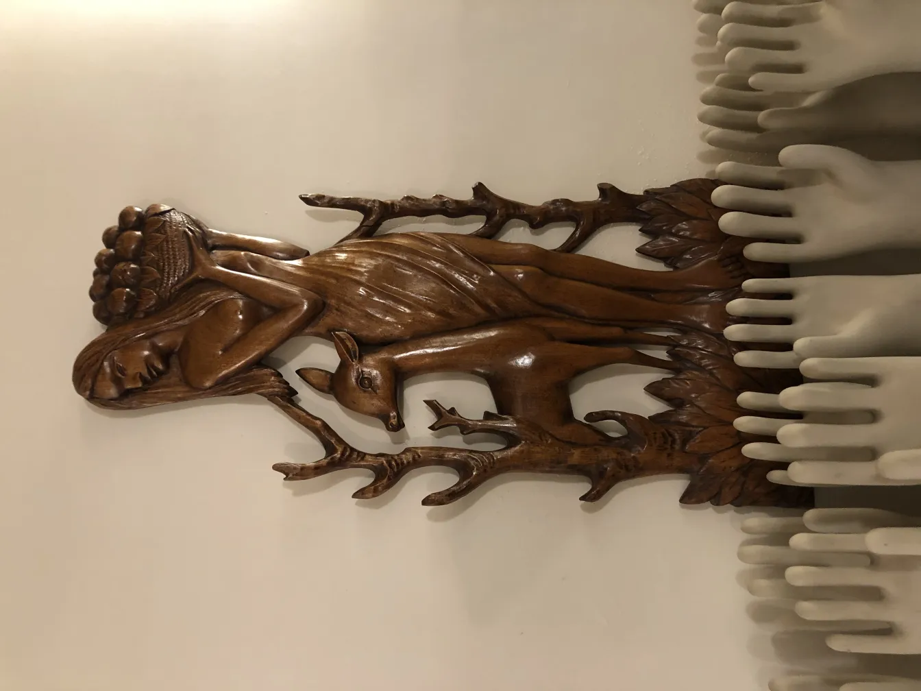 Antike Wandplatte mit Design einer menschlichen und einer Rehfigur, dekorativ in einem neutralen Umfeld.