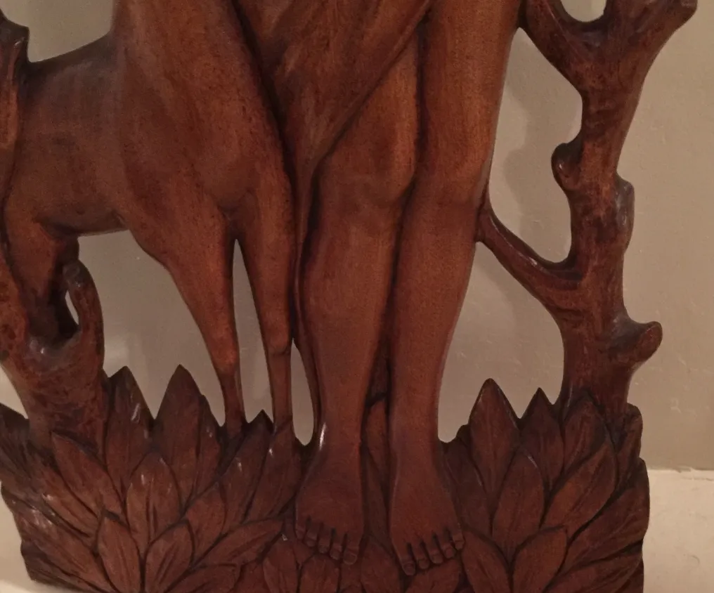 Placa de parede antiga apresentando uma figura estilizada com detalhes decorativos ao fundo.