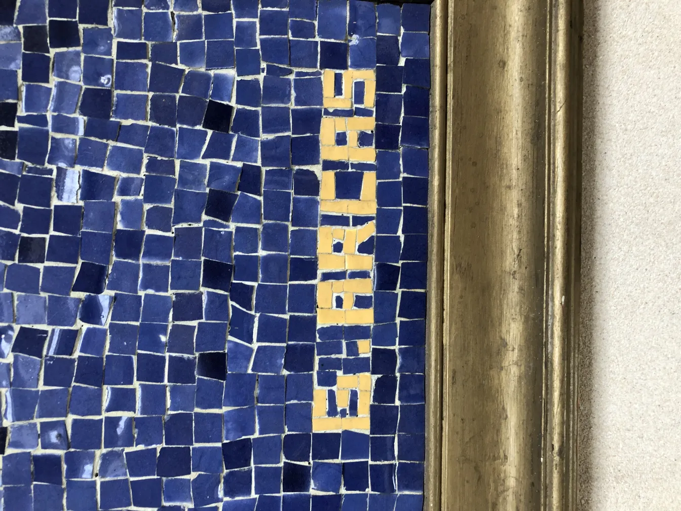 Antikes Mosaikbild mit blauen und gelben Fliesen, klassisches Umfeld.