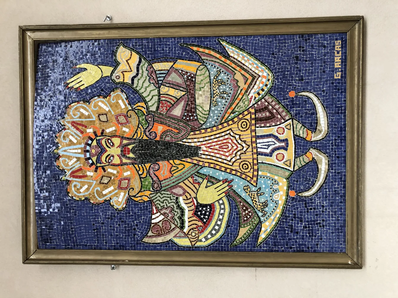 Cuadro de mosaicos antiguo con colores vivos sobre fondo azul.
