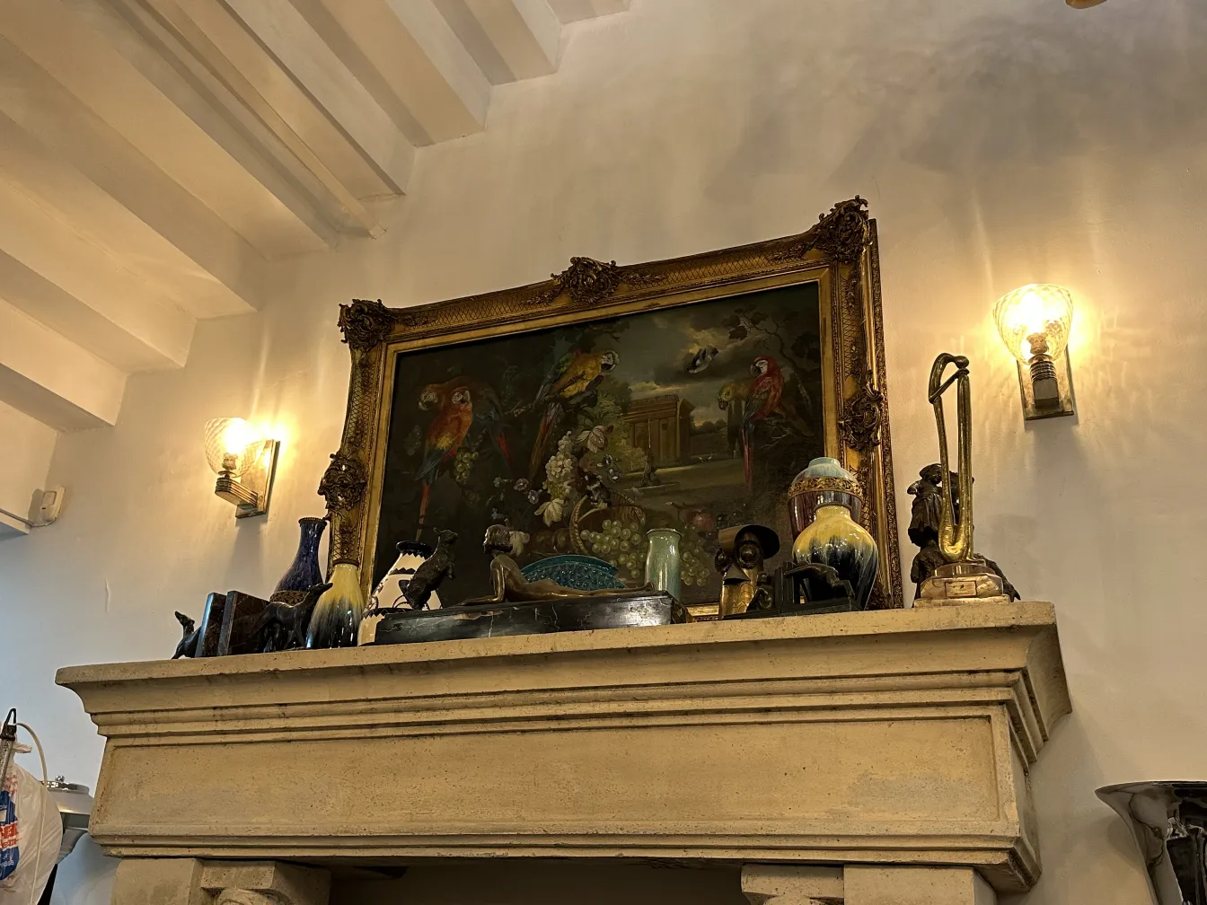 لوحة قديمة مؤطرة تحتوي على طيور وزهور، في بيئة ريفية.