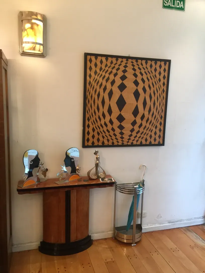 Antico intarsio su una parete bianca, con forme geometriche in toni scuri e chiari, che spiccano in un ambiente accogliente.