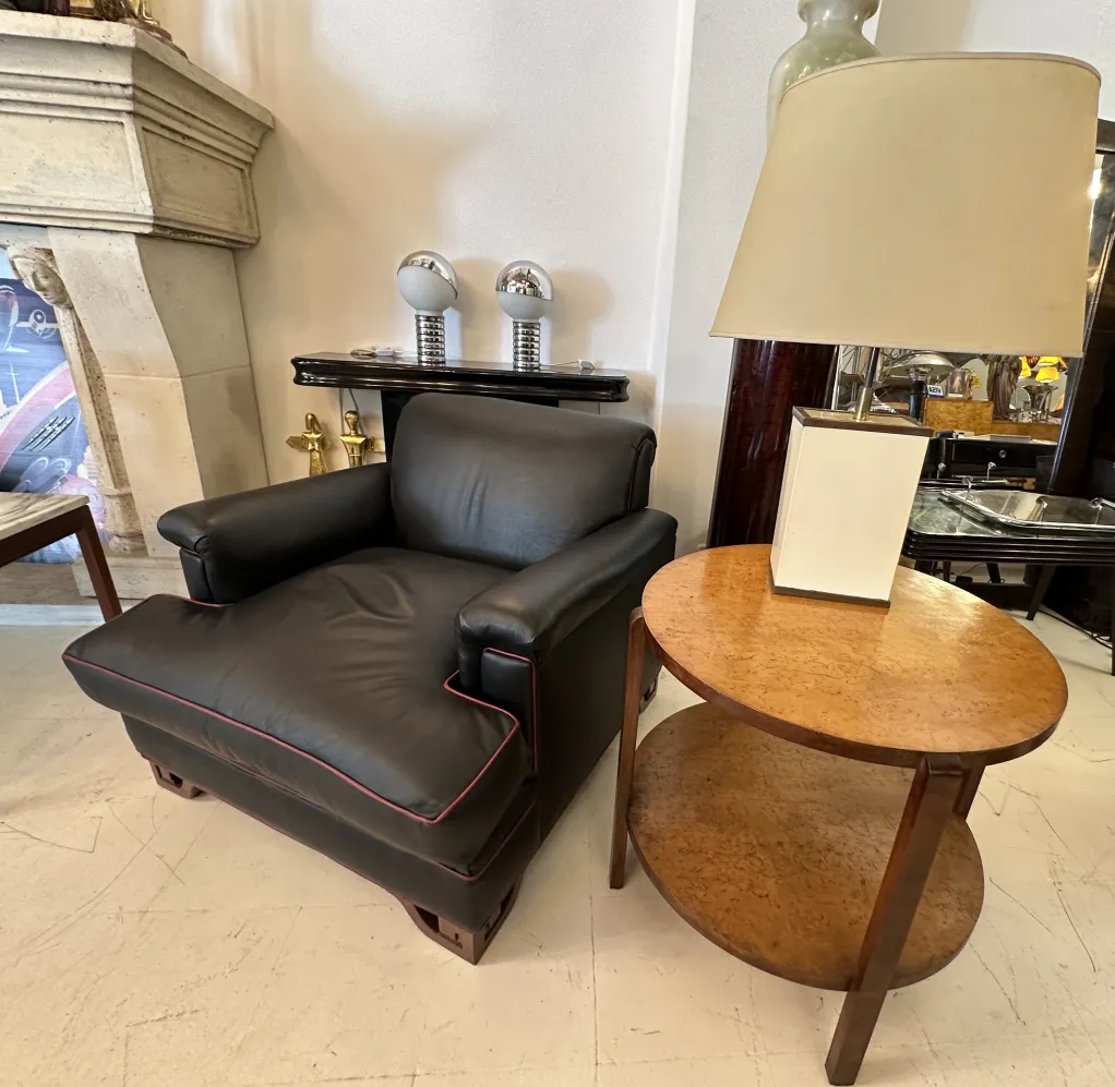 two antique table lamps next to a black armchair and a table