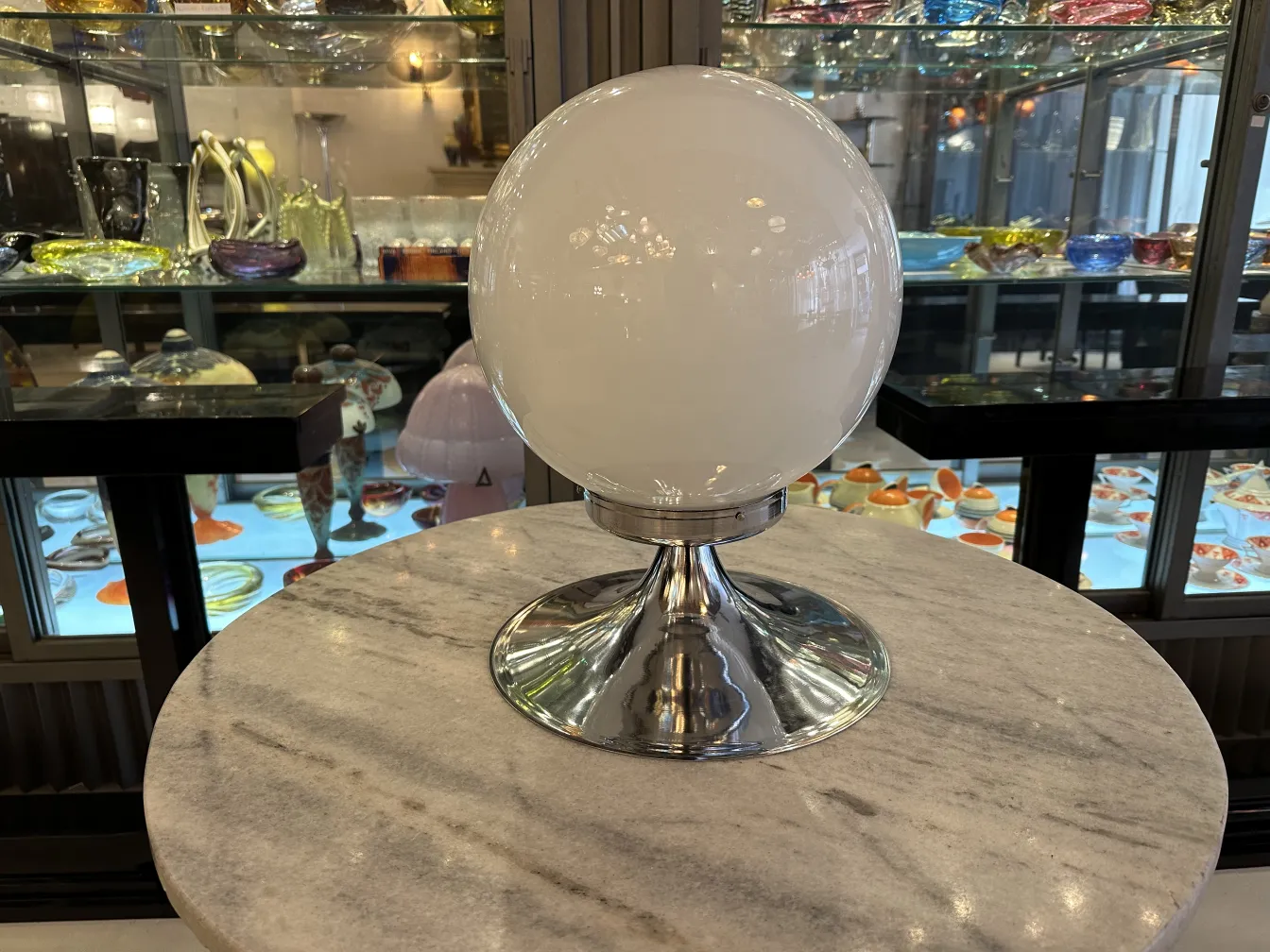 duas lâmpadas de mesa antigas de forma esférica com base brilhante, fundo de vitrine com itens antigos