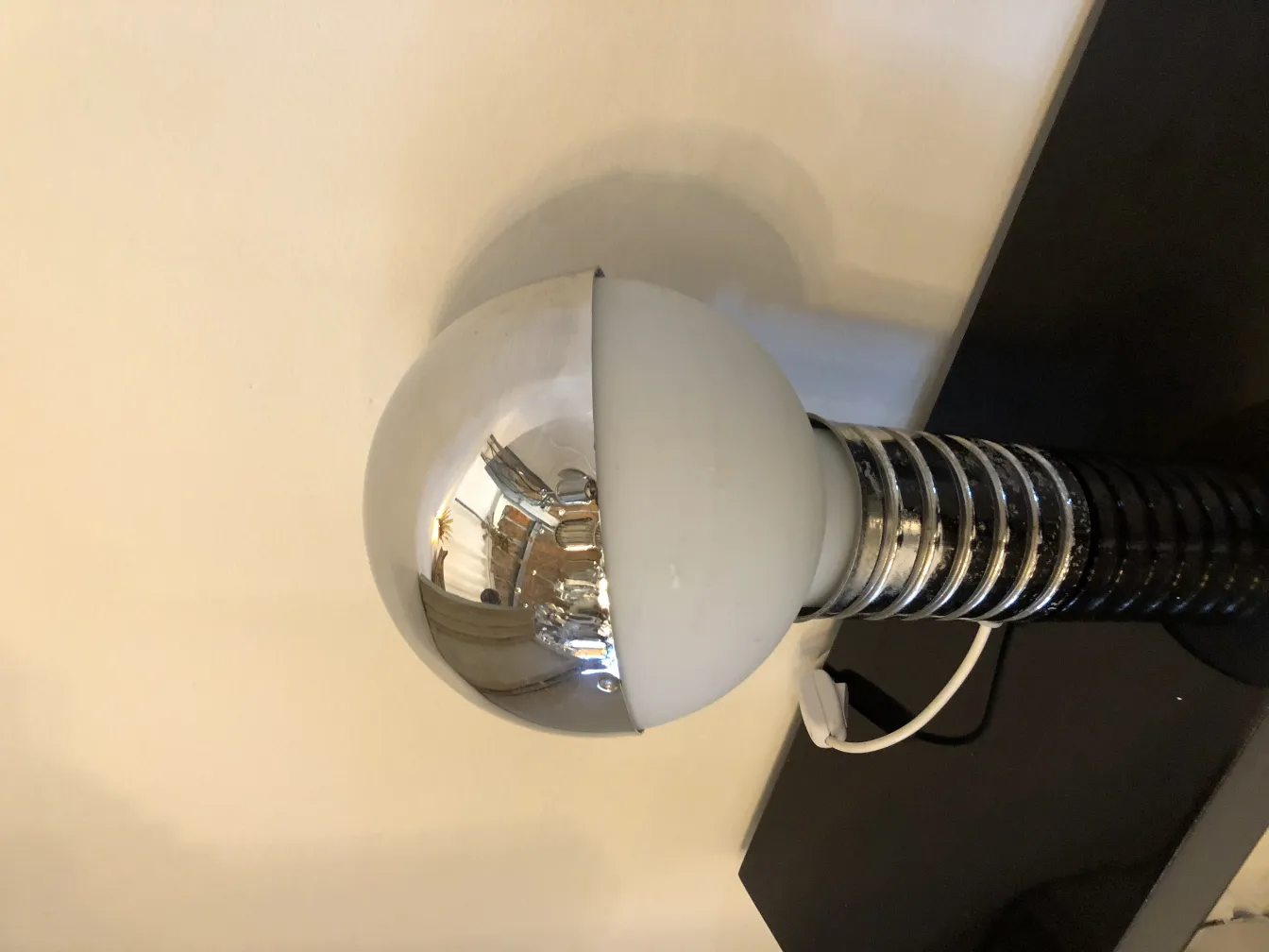 2 antigas lampadas de mesa com esfera brilhante e base preta, em um ambiente minimalista.