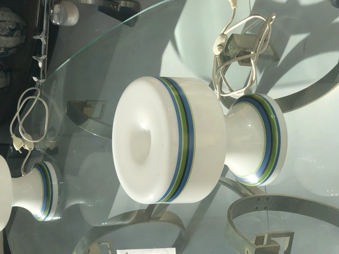 Vista de 2 lâmpadas de mesa antigas com detalhes coloridos. Ambiente aconchegante.