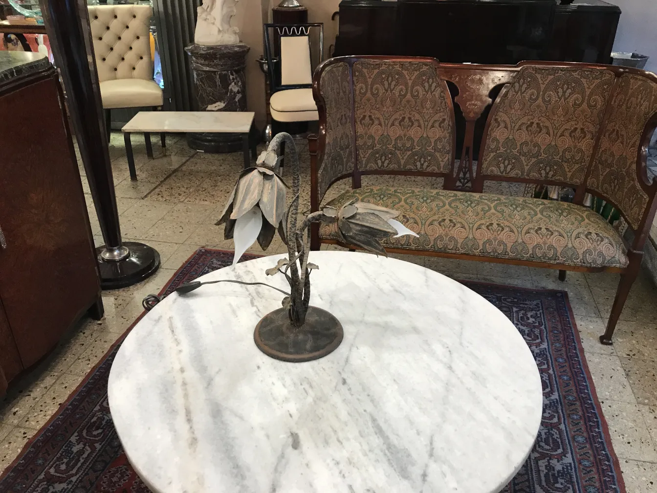 lámpara de mesa antigua con base de flores sobre mesa de mármol