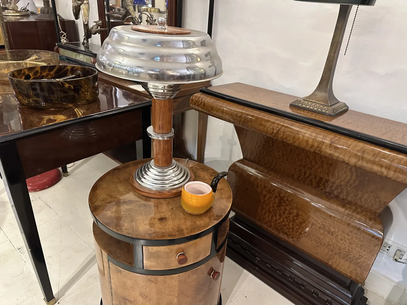 Deux lampes de table anciennes avec des couleurs métalliques et des détails décoratifs, à côté d'autres objets vintage.