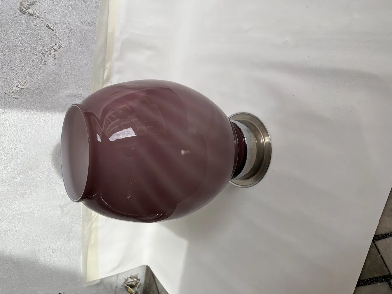 deux lampes de table anciennes, avec une base en métal et une couleur bordeaux, sur une surface blanche.