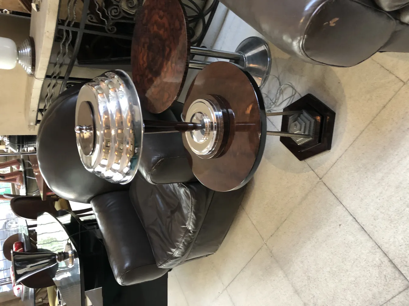 Duas lâmpadas de mesa antigas com base redonda e cúpula elegante. Colocadas ao lado de uma poltrona de couro.