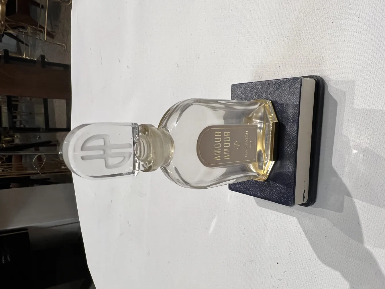 زجاجة عطر قديمة مع غطاء زجاجي مميز على قاعدة زرقاء.
