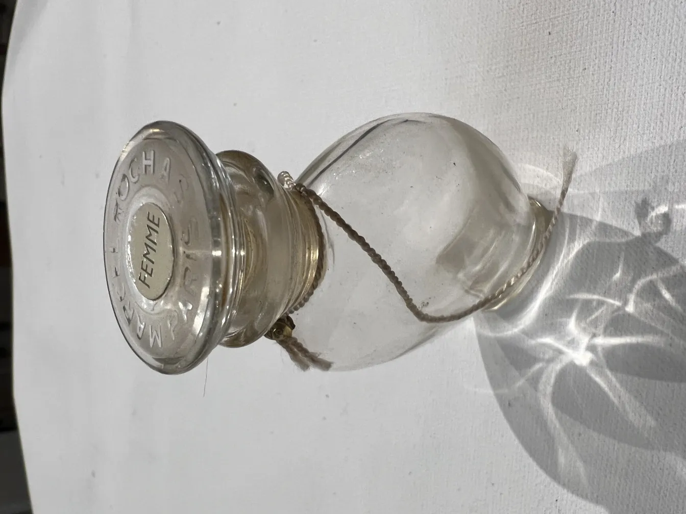 flacon de parfum ancien avec un couvercle décoratif et des détails complexes, illuminé par la lumière