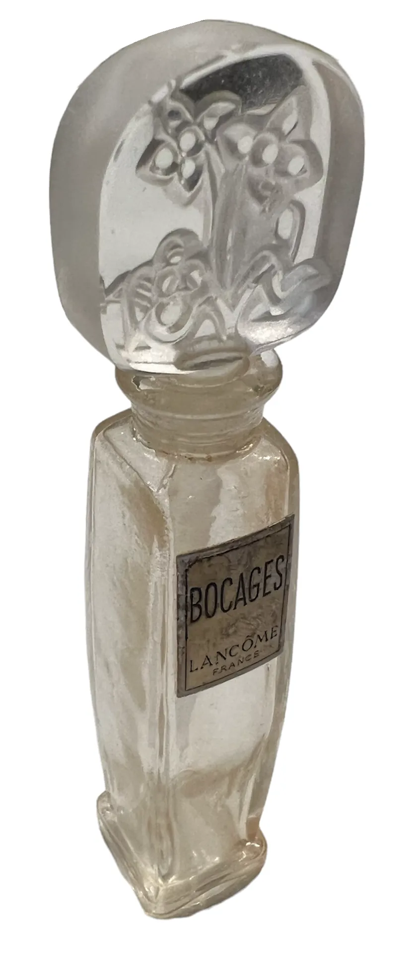 frasco de perfume antiguo con un tapón decorado, fondo claro