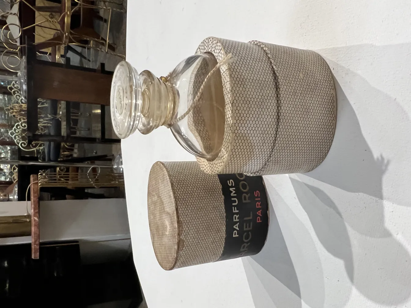 Flacon de parfum ancien avec étui décoratif, conçu avec élégance, dans un cadre nostalgique.