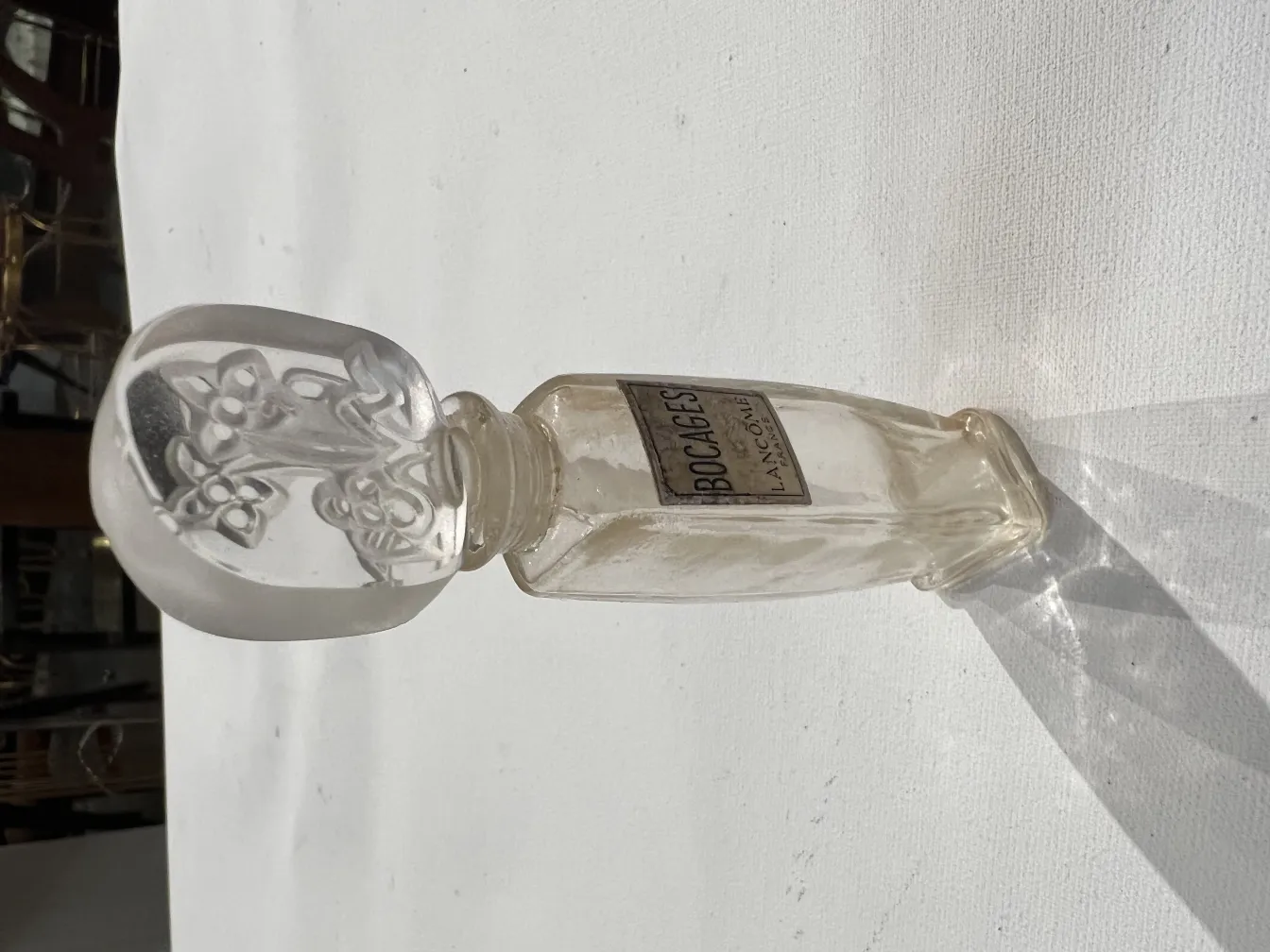 flacone di profumo antico con tappo decorato, luce soffusa e ombre