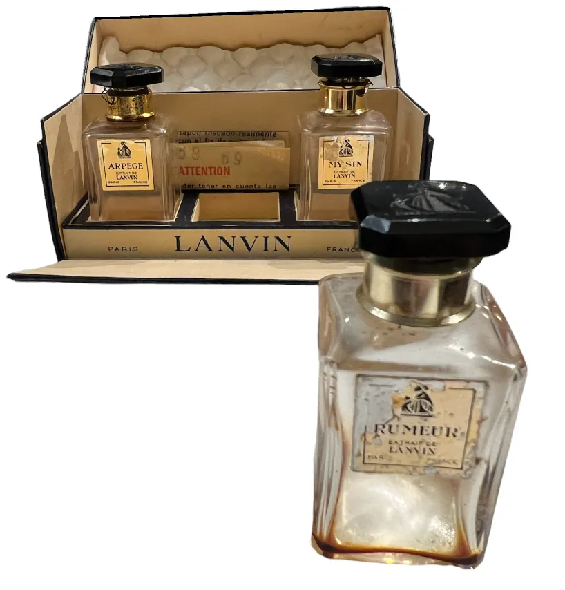 Antique Lanvin perfume bottle with golden details and other bottles in a case.
