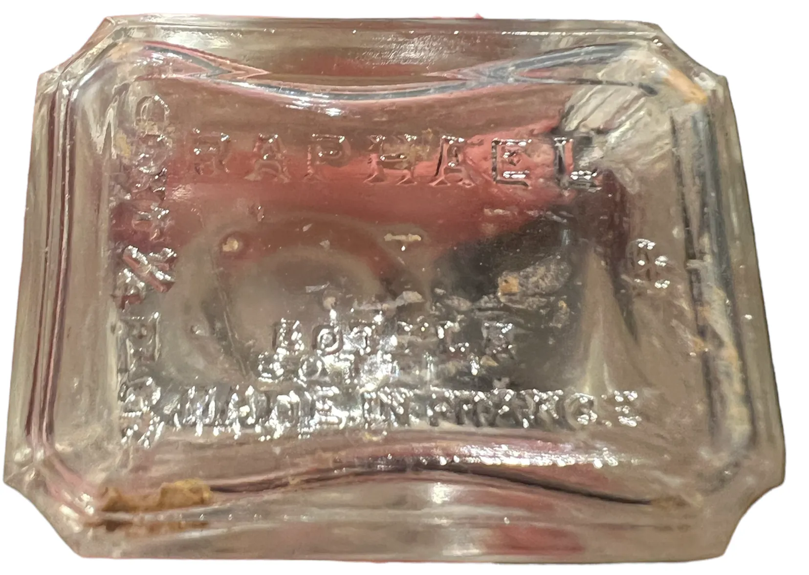 Flacone di profumo antico con iscrizione visibile, colore chiaro.