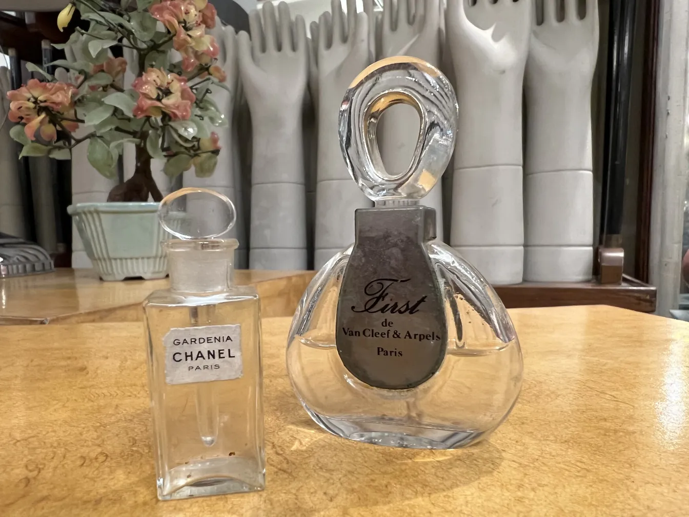 Antique perfume bottles from Chanel and Van Cleef on a wooden table.