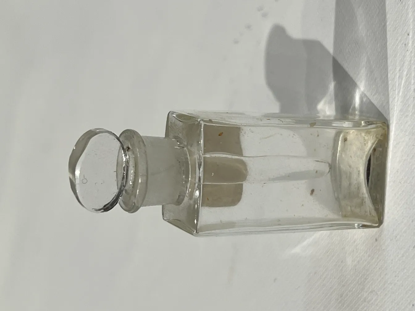 frasco de perfume antigo com tampa redonda e forma retangular