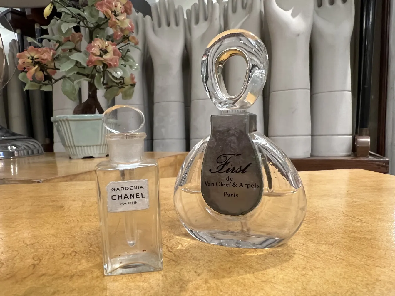 frasco de perfume antigo Gardenia Chanel em um ambiente elegante com flores ao fundo embaçado.