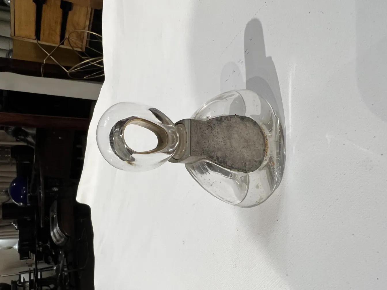 زجاجة عطر قديمة بتصميم أنيق وغطاء على شكل حلقة، على خلفية بيضاء