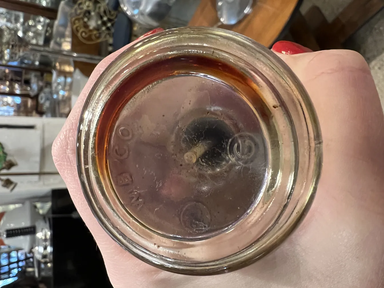 Obenansicht einer antiken Parfümflasche mit dunkler Flüssigkeit.