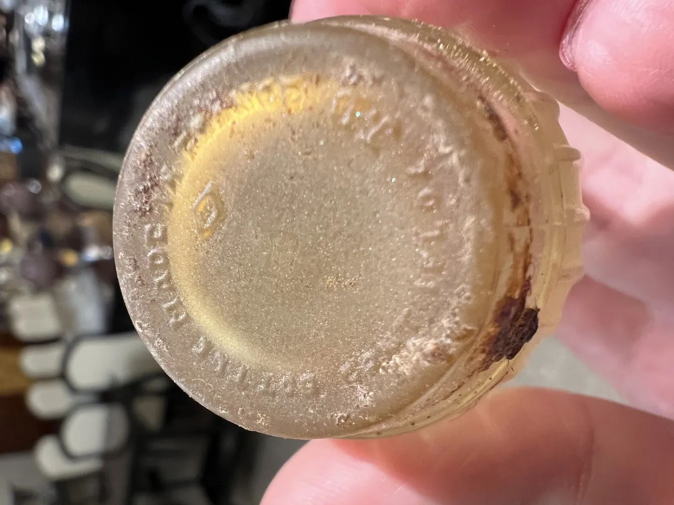 Antike Parfümflasche mit Details am Boden, goldene Farbe, abgenutztes Aussehen.