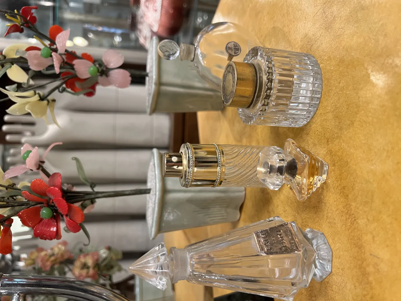 Various antique perfume bottles on a table, adorned with small flowers.