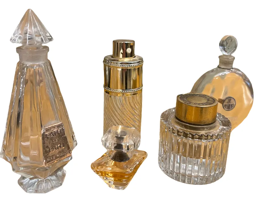cuatro frascos antiguos de perfume en diferentes formas y tamaños sobre fondo blanco