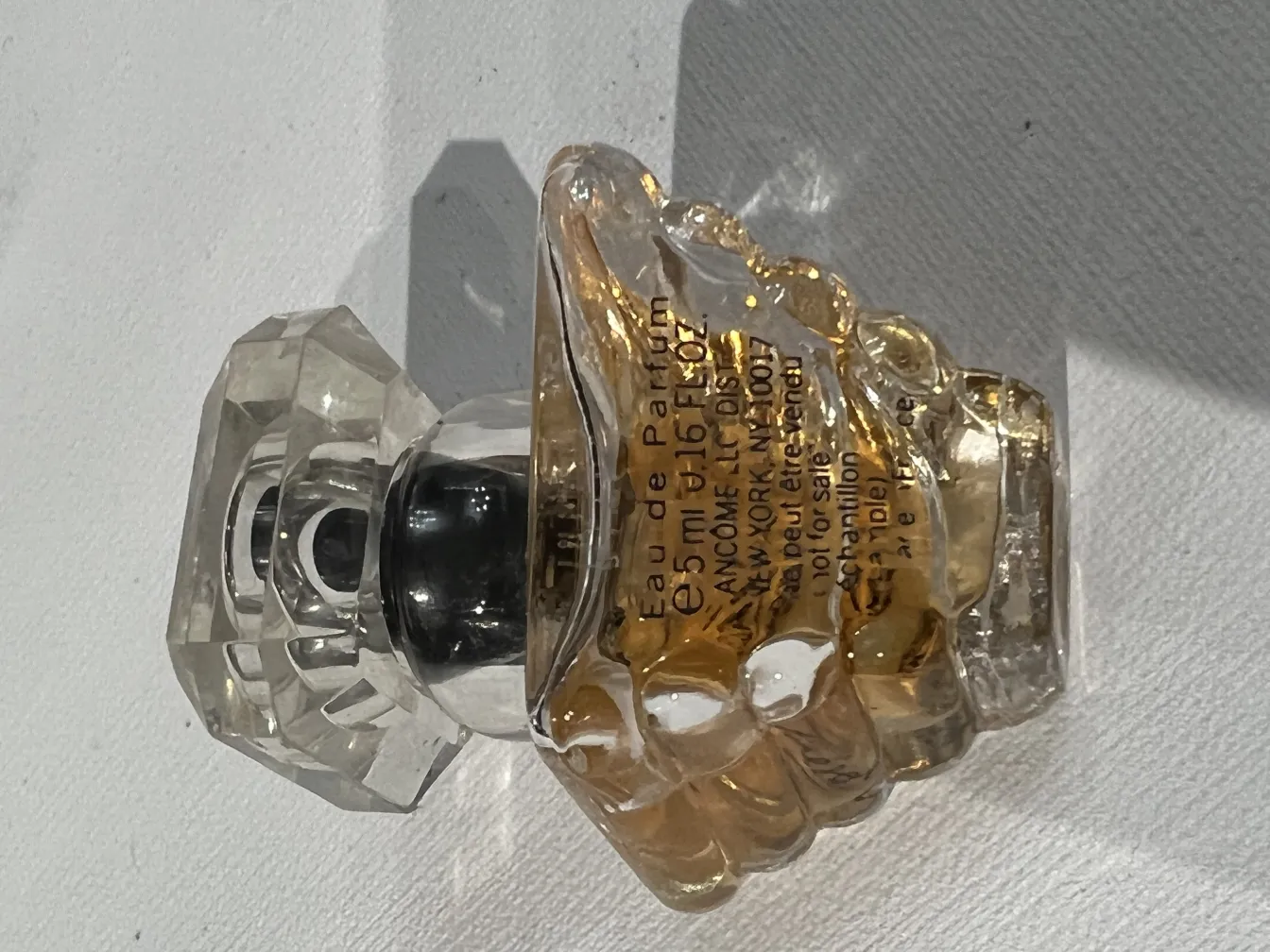 Flacon de parfum ancien avec bouchon facetté et liquide jaune.