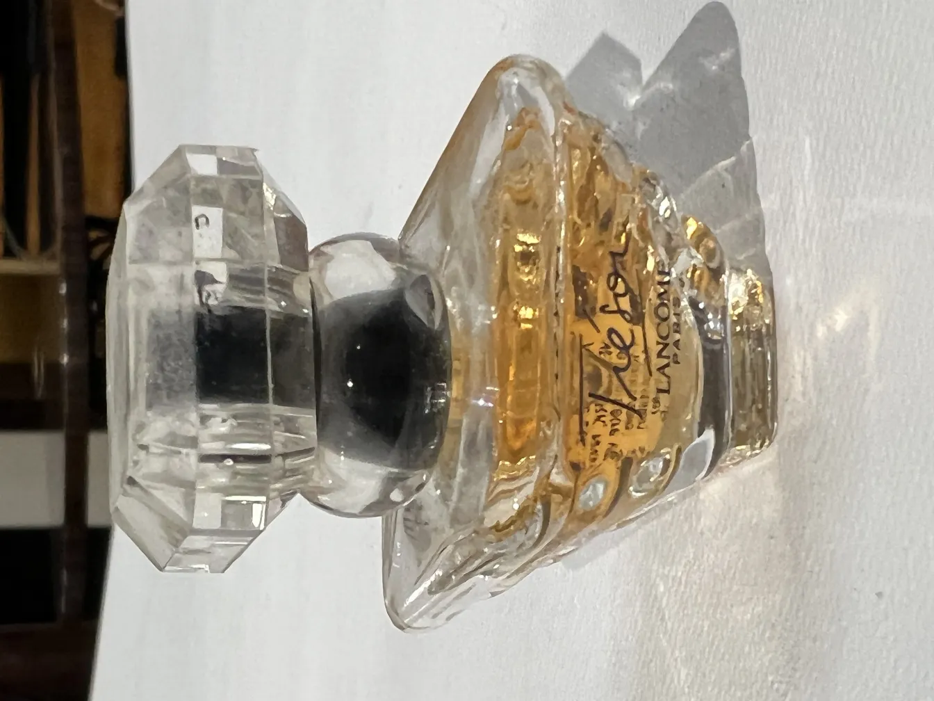 Frasco de perfume antigo com tampa de vidro, frente decorativa.