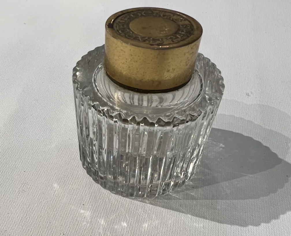 flacone di profumo antico trasparente con tappo dorato, dettagli complessi e ombre delicate