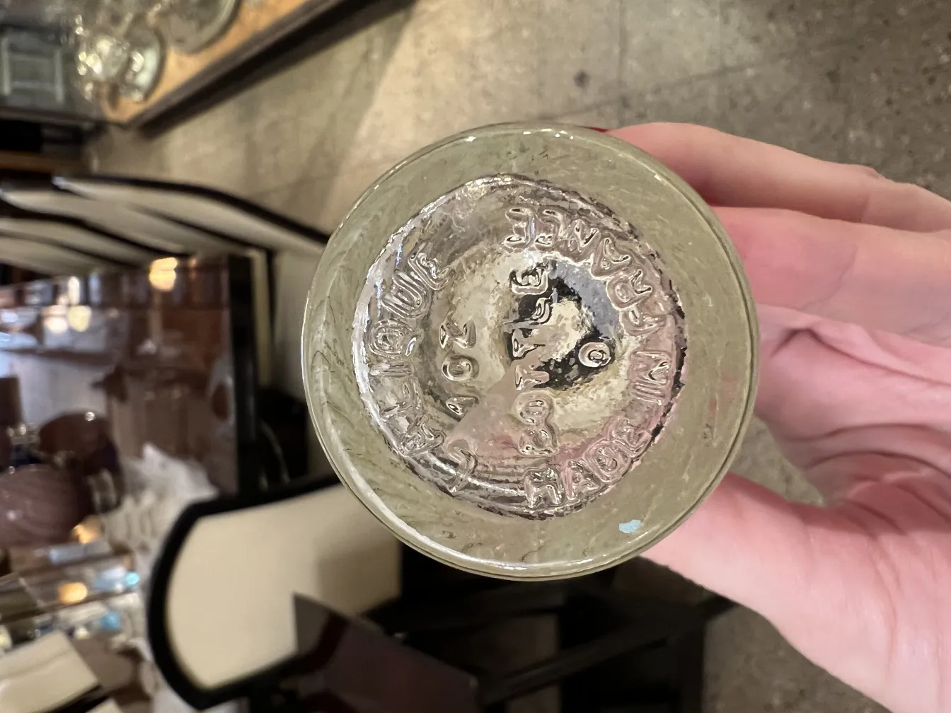 Flacone di profumo antico con dettagli visibili e forma elegante, su sfondo di mobili classici.