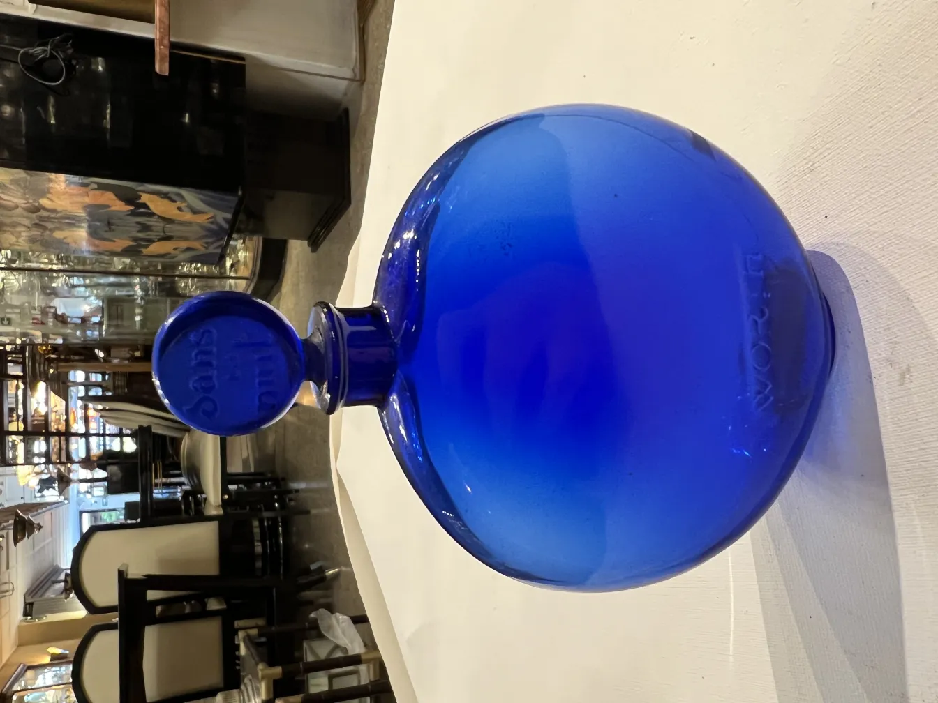 flacon de parfum ancien bleu, rond et élégant, dans un environnement classique