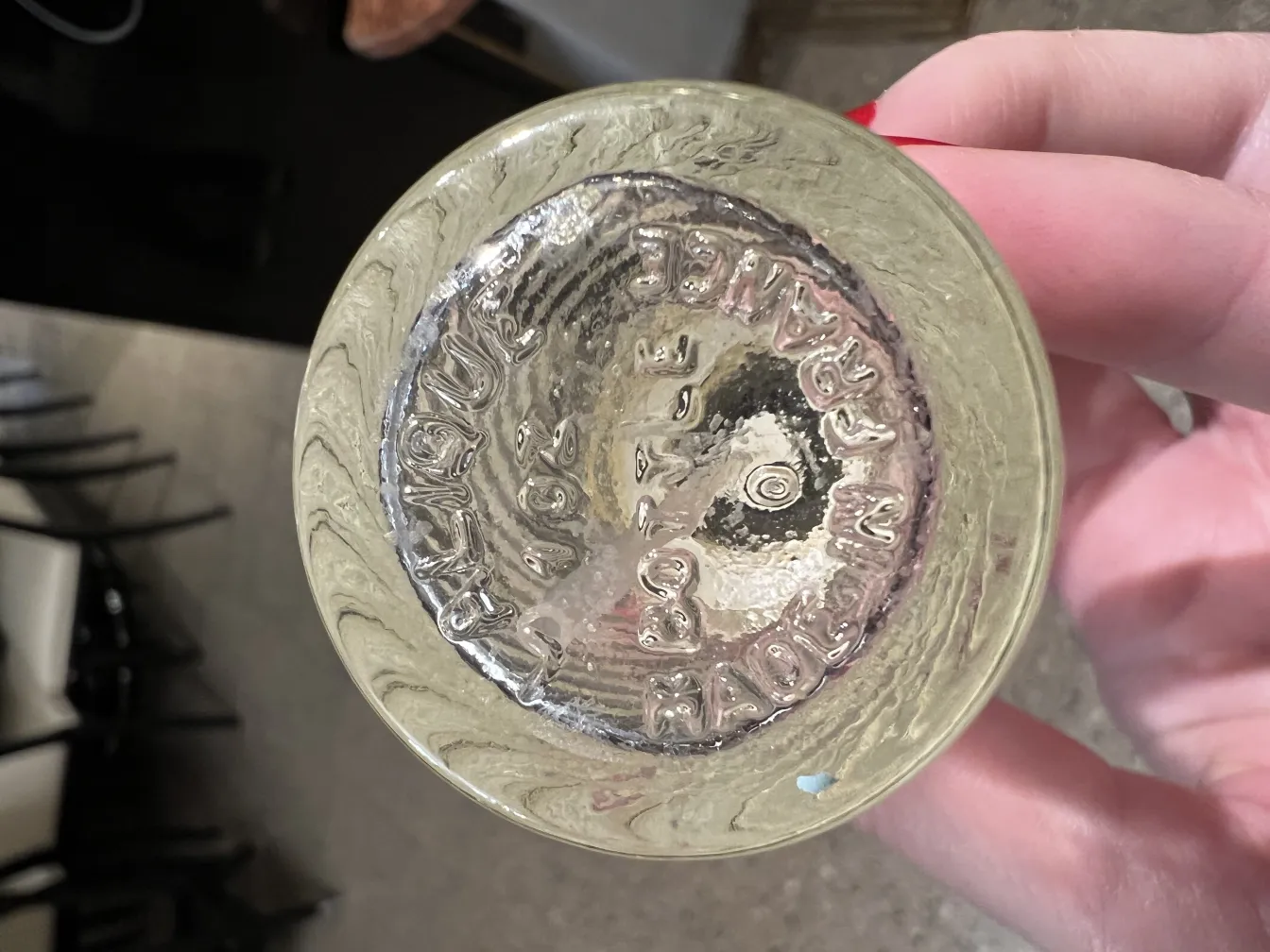 古い香水瓶の底にエレガントなデザインと波状模様があり、無地の背景に展示されている。