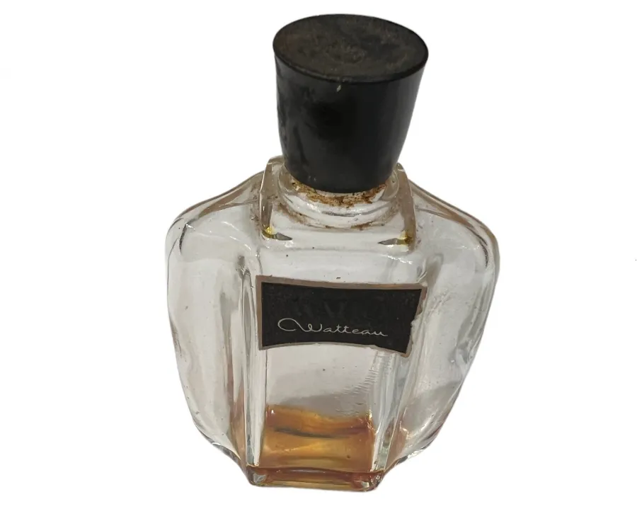 Flacon de parfum ancien avec bouchon noir, design élégant, verre clair et liquide doré