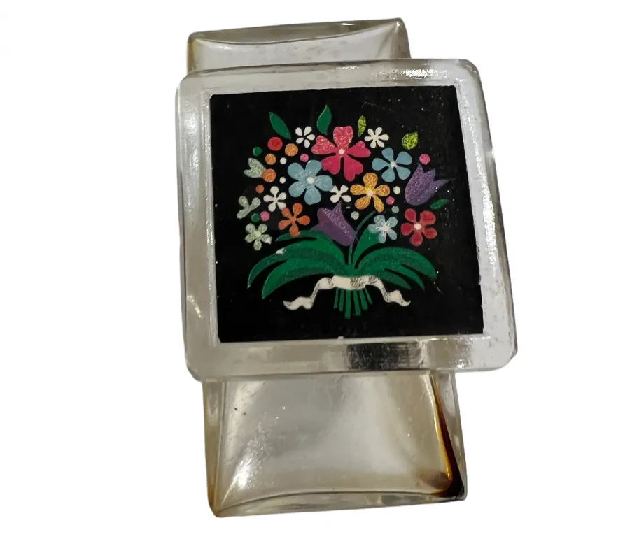 Flacone di profumo antico con design floreale colorato su sfondo nero, decorazione allegra.