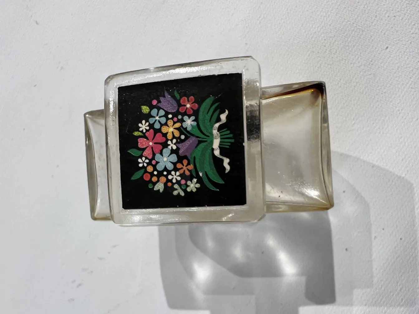 flacone di profumo antico con fiori su sfondo nero