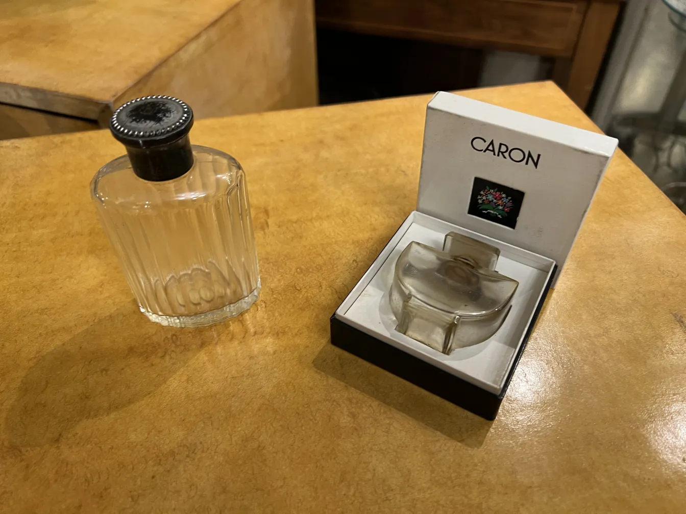 زجاجة عطر قديمة ذات غطاء أسود، على سطح خشبي