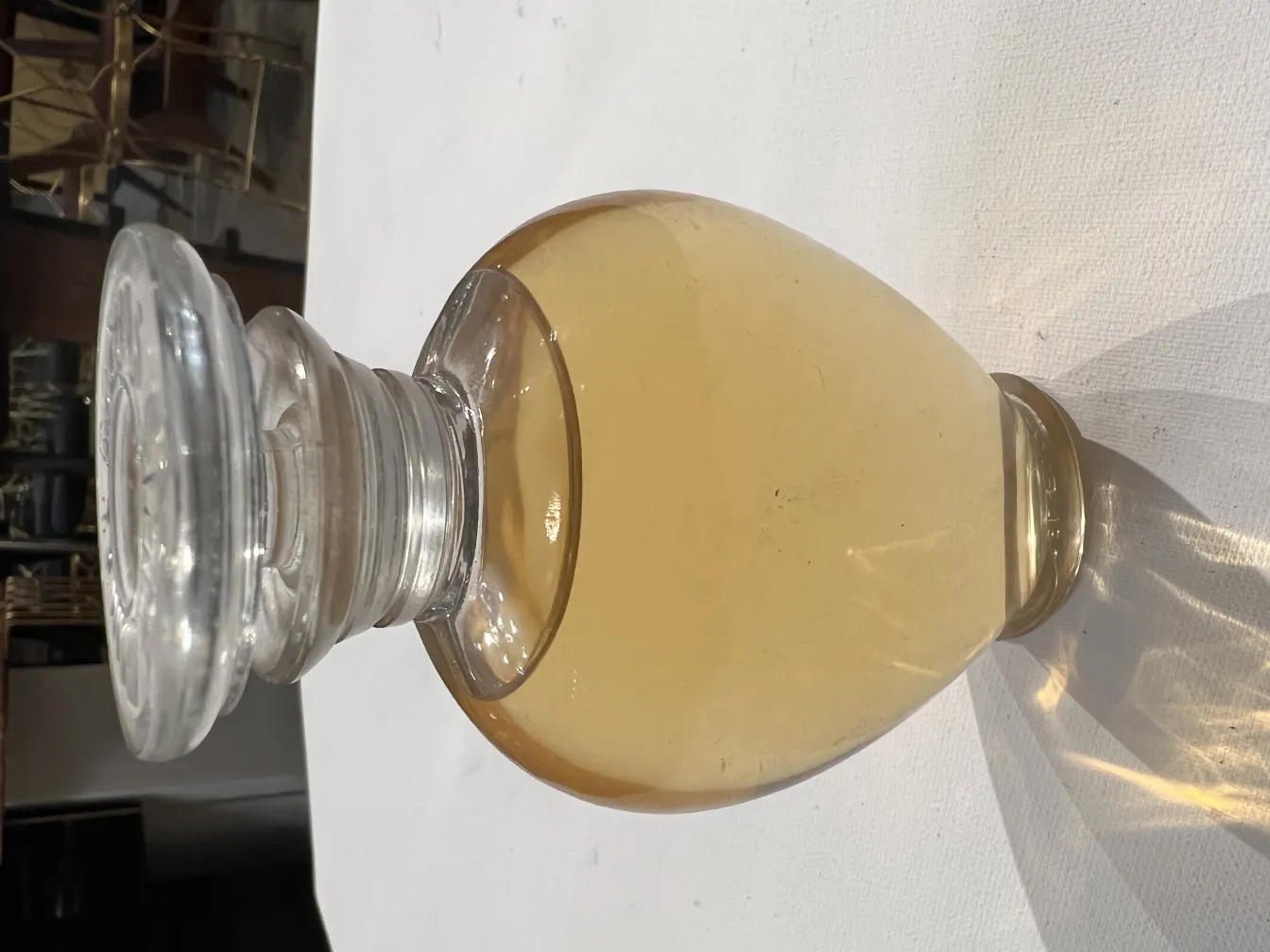 antique perfume bottle with light yellow liquid and cap