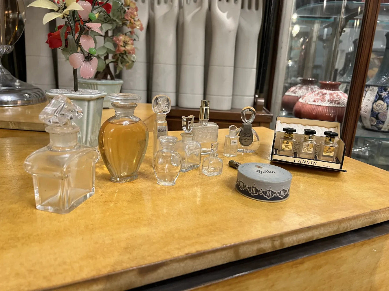 antike Parfümflasche auf einem Tisch mit anderen Flaschen und Blumen