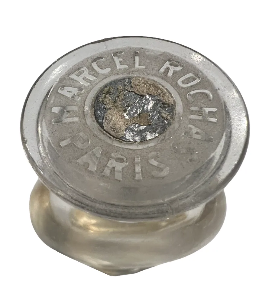 frasco de perfume antiguo con tapa marcada y detalles visibles.