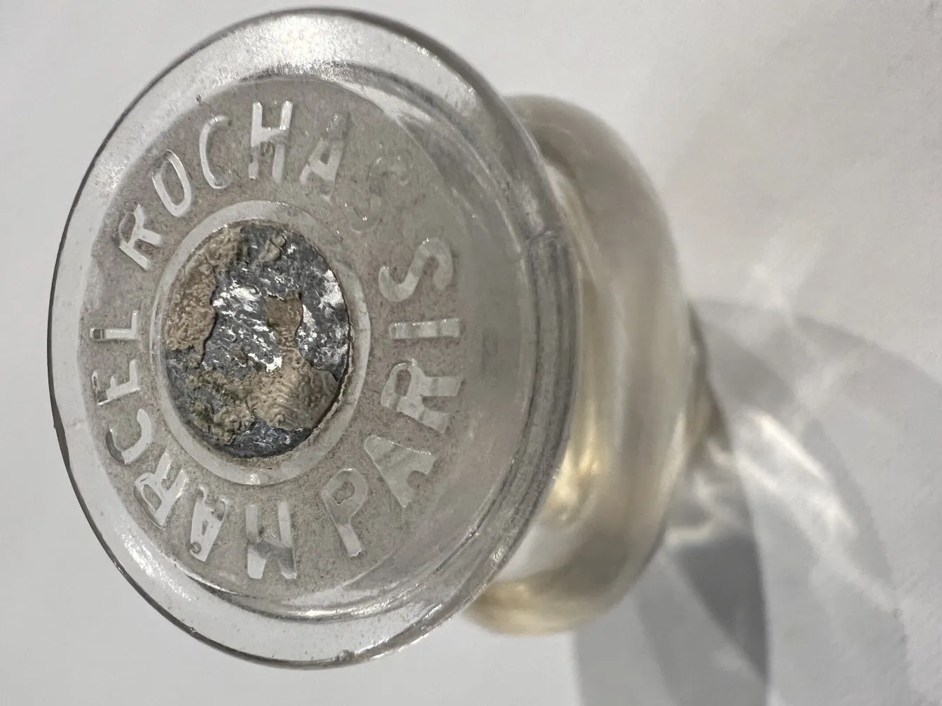 زجاجة عطر قديمة مع ملصق ظاهر في القاعدة، خلفية محايدة