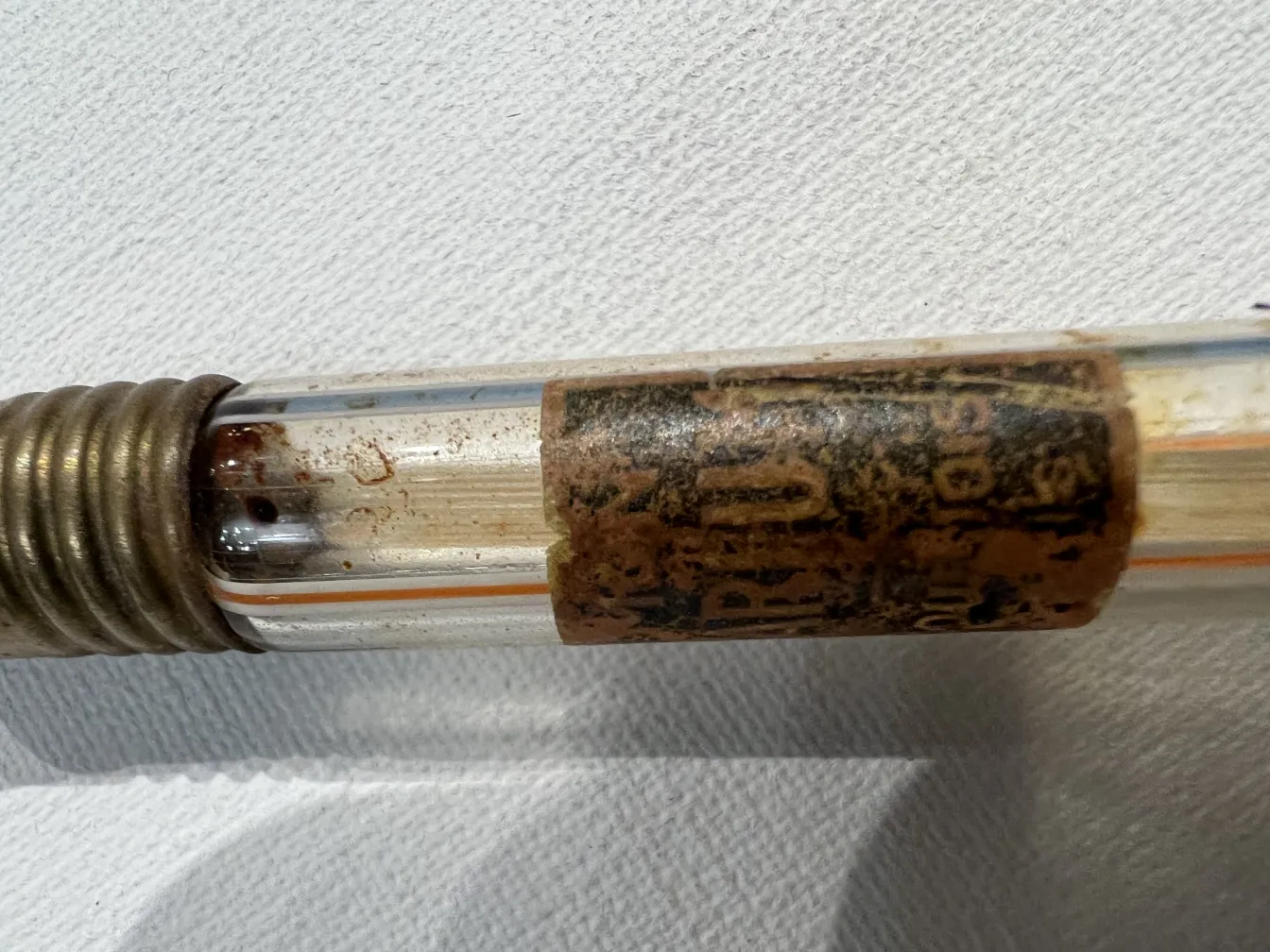 frasco de perfume antiguo con etiqueta desgastada, visible parte metálica.