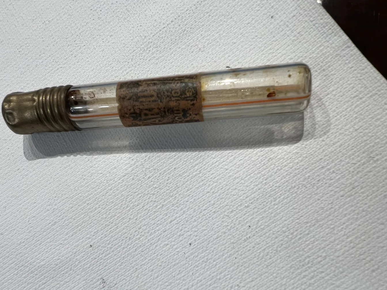 古董香水瓶，带金属盖，上面装饰着标签和浅色，背景为白色。