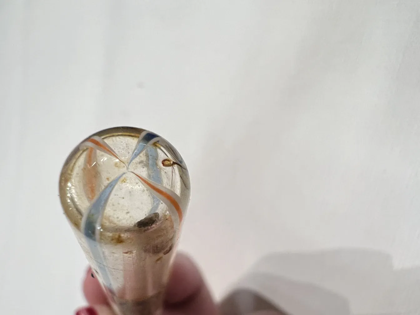 Frasco de perfume antigo com decorações coloridas, visto de cima.