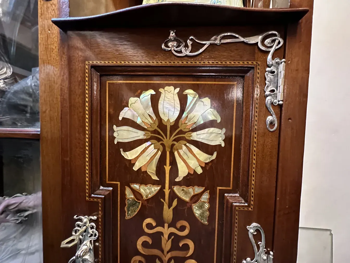 Antique display cabinet featuring intricate floral and butterfly designs, elegant and decorative.