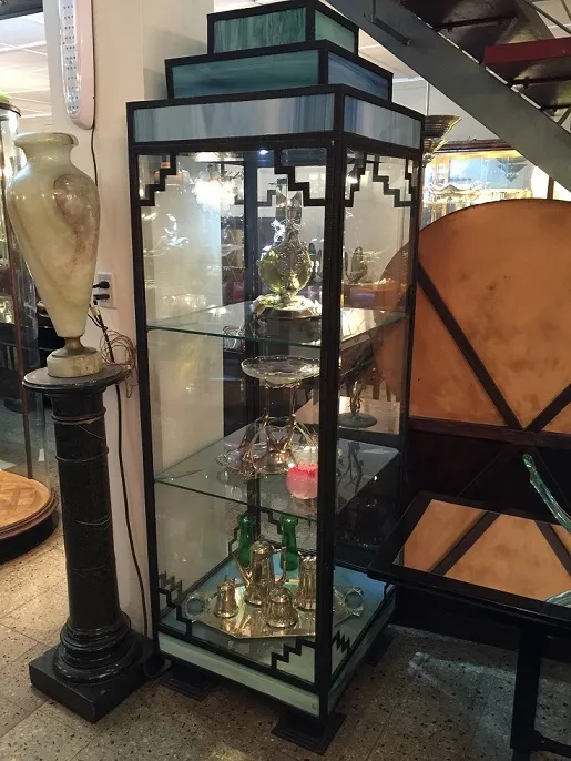 Vitrine antiga com objetos decorativos e fundo iluminado.