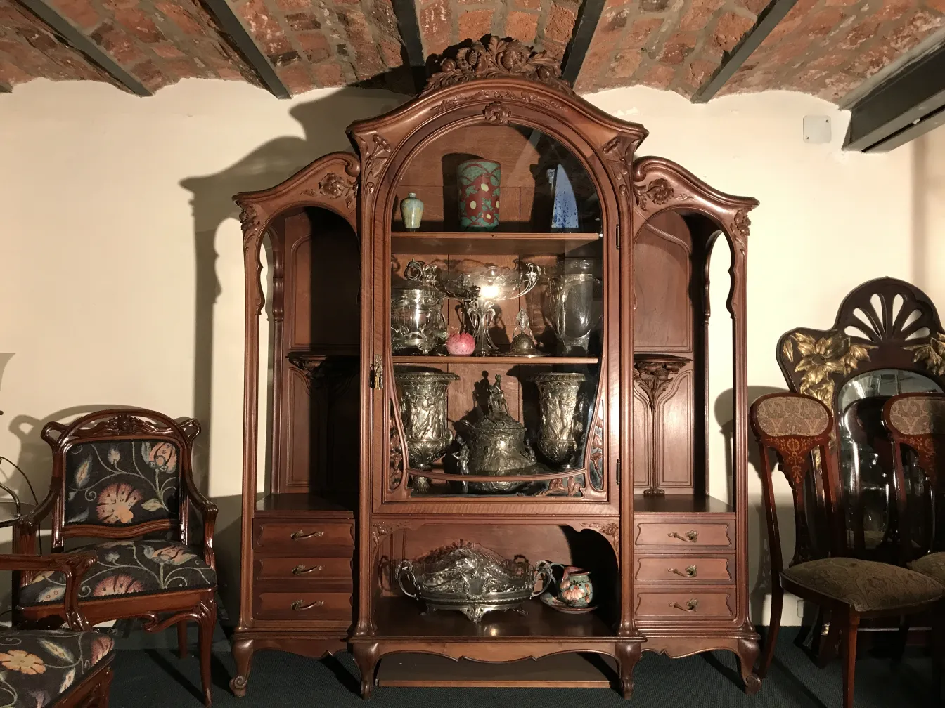 Antique display cabinet with ornamental details and silver objects