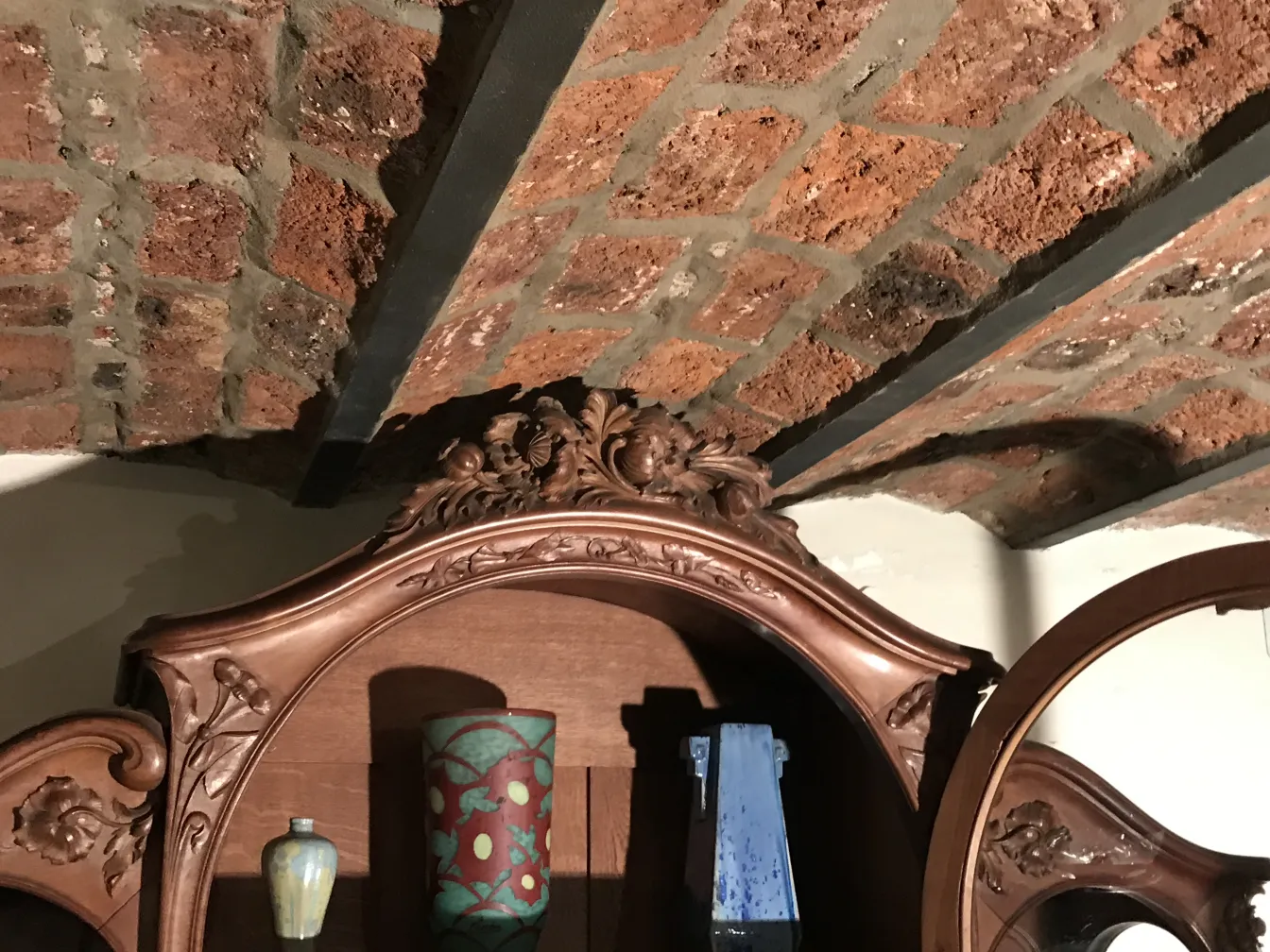 vitrine antique en bois, ornée de détails sculptés, présentant des objets décoratifs à l'intérieur